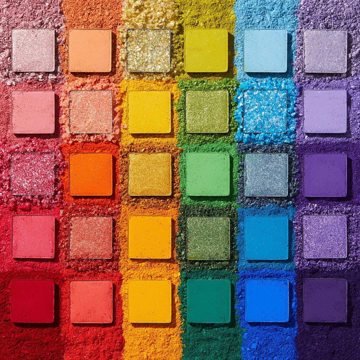 Fade Into Hue shadow palette displays 30 square pans in a rainbow grid - matte, shimmer, and pressed glitter - set on crushed pigment in a deconstructed flat lay; a vibrant ColourPop Shadow Palette.