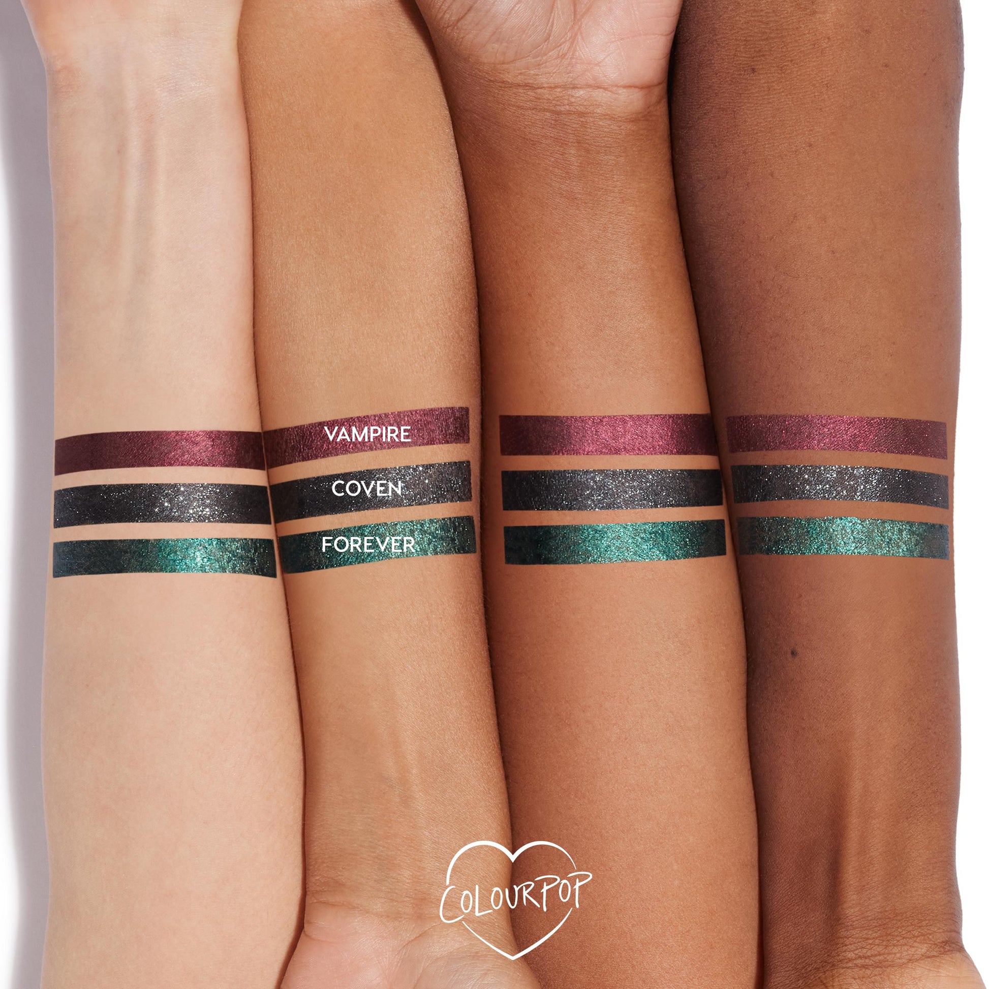 ColourPop Coven Graphix Ink Liner swatched on three forearms - a sparkly charcoal-black stripe centered between metallic burgundy Vampire and emerald-teal Forever - showing opaque payoff across multiple skin tones; ColourPop heart logo below.