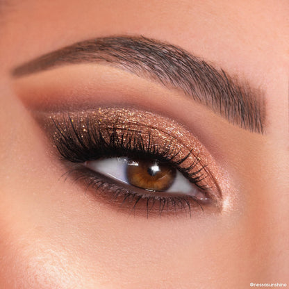 Shimmery bronze and copper glitter eyeshadow sweeps across a brown eye with long lashes and a defined brow, created using the Feelin Wild Shadow Palette Set, a ColourPop Shadow Palette, in a tight beauty close-up.